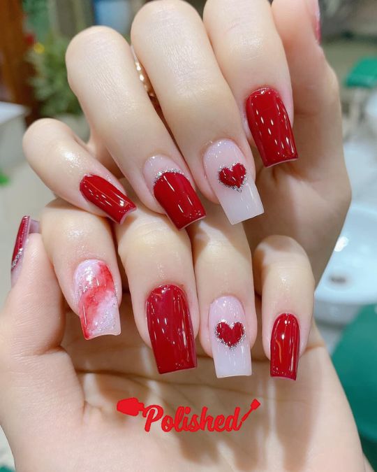 red square nails with glitter-trimmed heart accents on nude bases