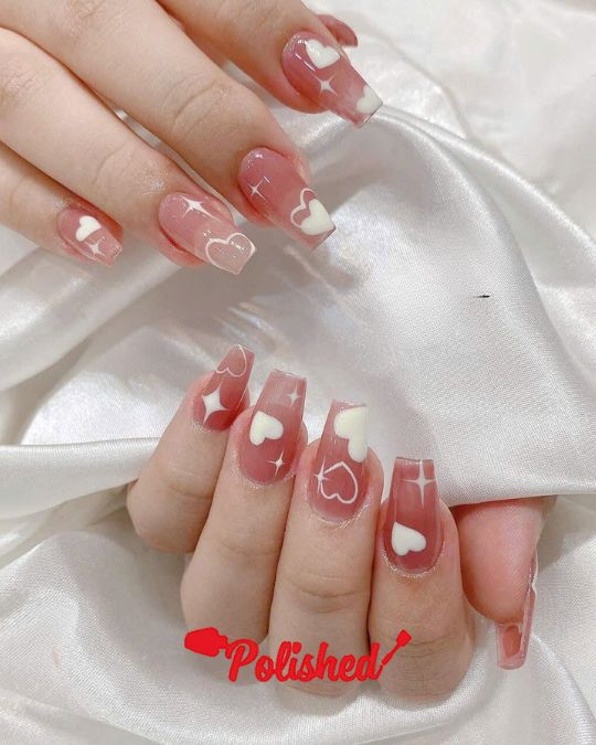 Translucent pink jelly nails adorned with white hearts and sparkling star accents