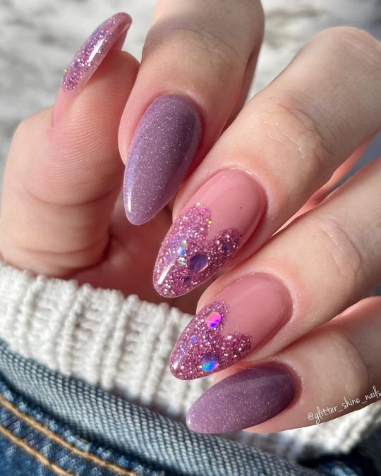 Almond-shaped nails blend soft pink and moody purple with dazzling glitter accents, evoking a starry evening sky