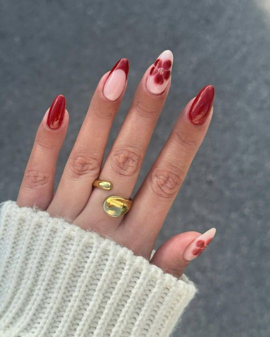 Almond-shaped nails featuring deep red and soft pink hues with delicate floral accents