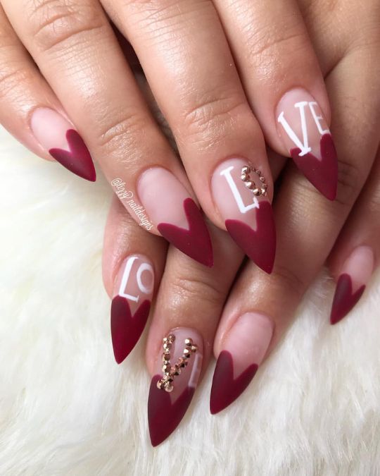 Stiletto nails featuring a pink base with deep burgundy heart-shaped for Valentine's Day Nails