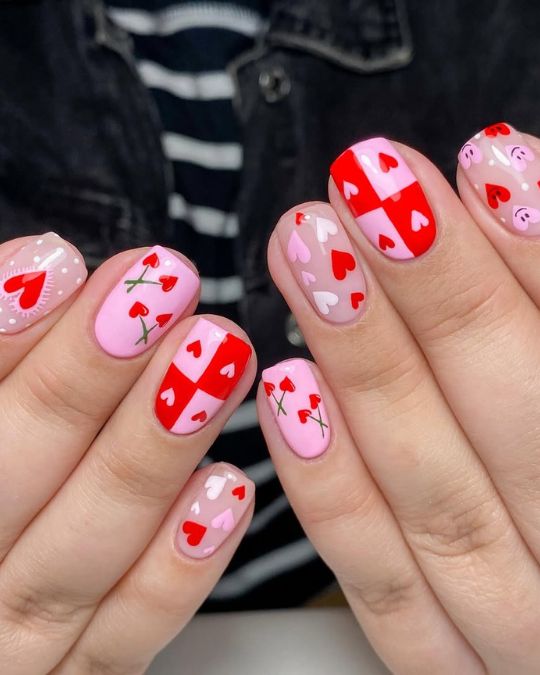 Short rounded nails featuring a variety of pink and red heart designs