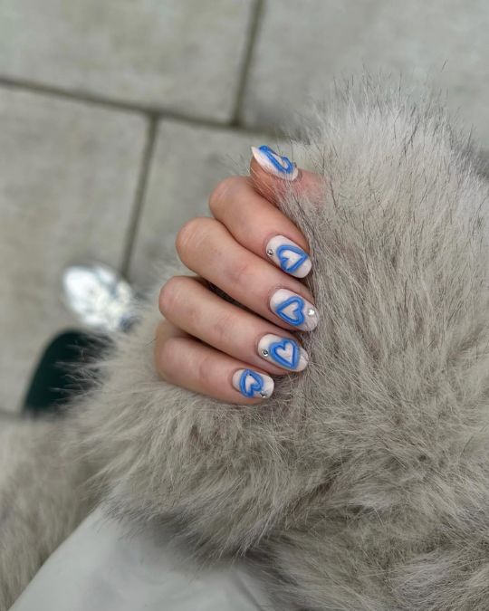 Round-shaped nails with blue heart swirls on a nude base
