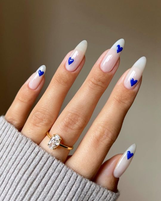 Almond-shaped nails with a crisp white base, adorned with vibrant blue heart 