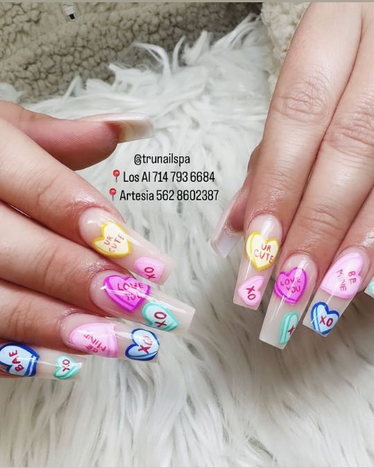 Clear square nails with pastel hearts and romantic messages.