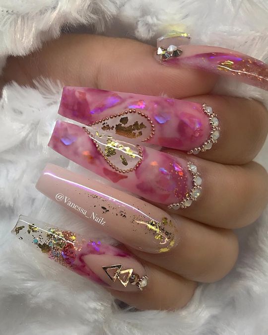 Elongated coffin nails showcase a mesmerizing blend of soft pink and rich purple tones, enhanced with luxurious gold highlights and sparkling crystal adornments
